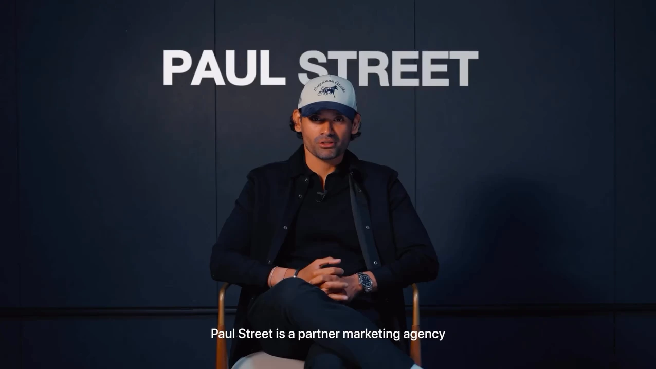 A man wearing a cap seated for an interview beneath large Paul Street text.